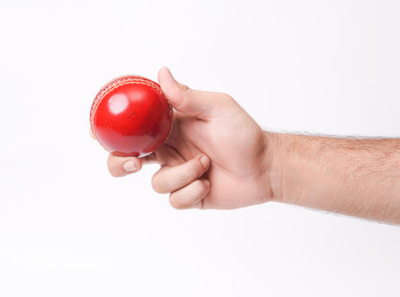 Closeup Photo Of A Male Bowler Firmly Gripping On A Red Test Match Cricket Ball On White Background