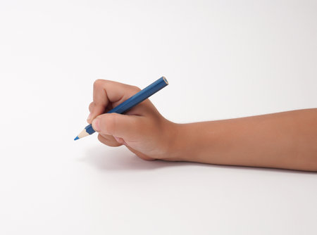 Childs hand holding blue pencil writing on white background with copy space.の写真素材