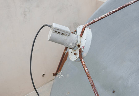 Close-up of satellite feedhorn mounted on blue dish with rusted support arms.の写真素材