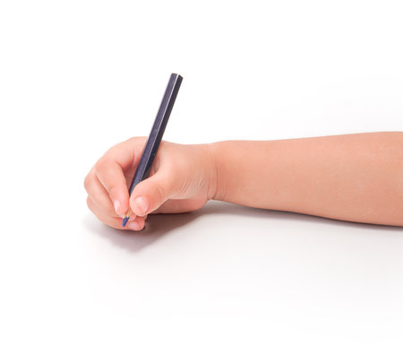A child's hand holding a blue pencil, writing on a white background.の写真素材