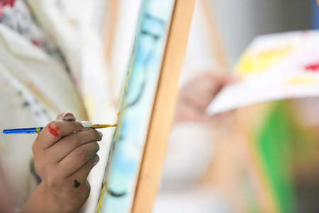 Close-up of a female artist painting a picture on canvas.の写真素材