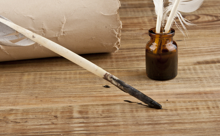 Old paper and feather with ink on a wooden tableの写真素材