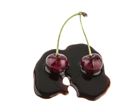red cherry in liquid chocolate isolated on white backgroundの写真素材