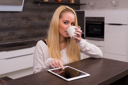 Young woman drinking coffee in kitchenの写真素材