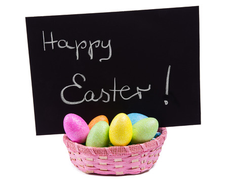 Colorful easter eggs in a basket and chalk happy easter letters の写真素材