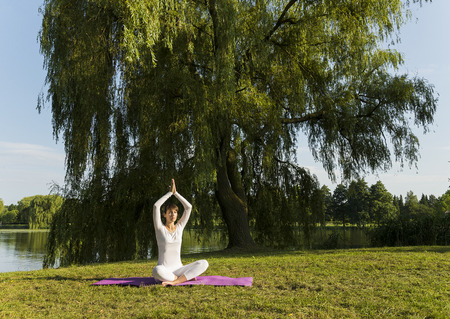 Pretty woman doing yoga exercises in the park.の写真素材