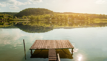 Pier in sunset at the lake. The trees reflection in lake.の写真素材