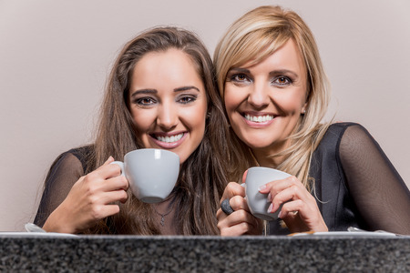 Two smiling attractive women having a cup of coffee in a coffee shop.の写真素材