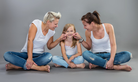 Two beautiful women making fun with a litte toothless girl.の写真素材