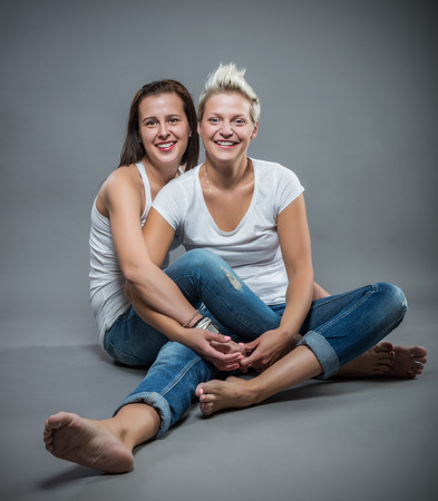 Two young cheerful sister hugging in the studio.の写真素材
