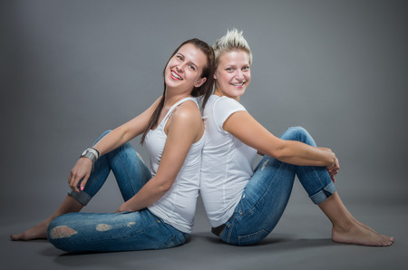 Two young cheerful sister hugging in the studio.の写真素材