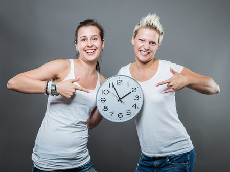 Portrait of beautiful smiling women holding a big clock in her hands.の写真素材