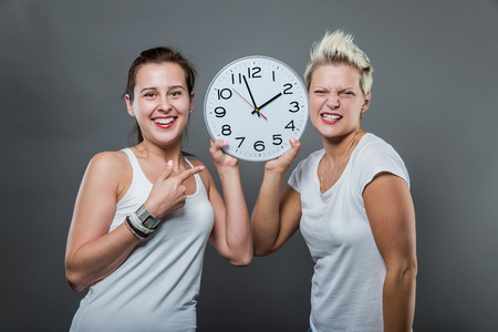 Portrait of beautiful smiling women holding a big clock in her hands.の写真素材