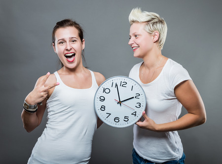 Portrait of beautiful smiling women holding a big clock in her hands.の写真素材