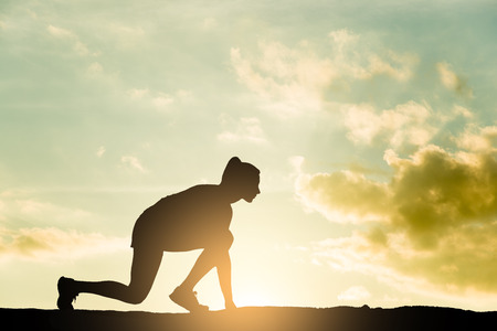 Athlete runner woman starting run at sunsetの写真素材
