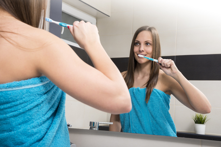 Portrait of attractive woman brushing teeth in bathroomの写真素材