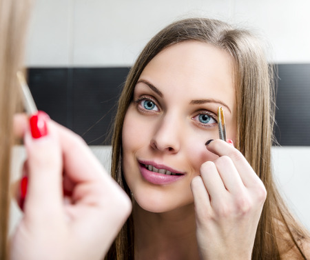 Beauty fresh model girl shaping eyebrows with tweezerの写真素材