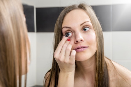 Young woman putting contact lens in her eye close upの写真素材