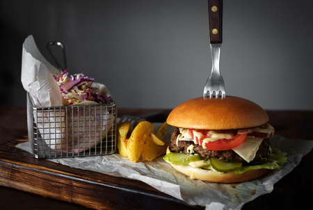 Burger, homemade cheese and cucumbers next to salad and a baked potato. Wooden table in the background. Burger stuck plugの写真素材
