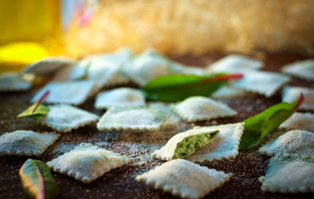 Homemade raw ravioli with spinach and ricotta on wooden Boardの写真素材