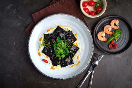 cooked black ravioli with shrimp and greens serve on a white plate, top viewの写真素材