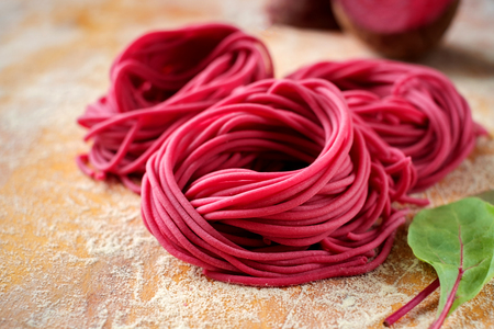 Hand made beetroot pasta nest on a wooden table. Raw purple spaghettiの写真素材