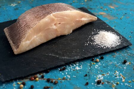 fresh steak raw fish halibut on the stone with the salt and herbs on wooden background