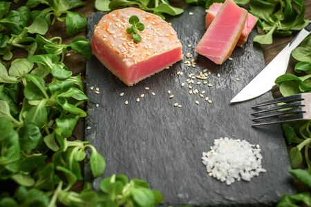 cooked tuna steak rests on a stone Board with a green salad closeupの写真素材