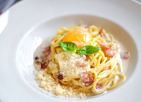 Pasta Carbonara with bacon Parmesan and egg yolk on a white plate, macroの写真素材