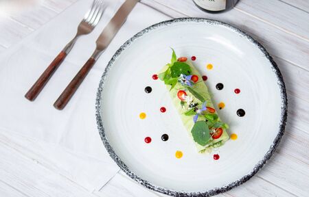 Cucumber rolls with greens, salad and cabbage. Vegetable roll, serving at the restaurant on a white plate, top viewの写真素材