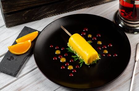 Italian Limoncello dessert on black plate. Lemon cake with mint and pistachio.