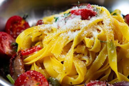 Homemade tagliatelle pasta with sun dried tomato, parmesan and herbs on metal bowl. Traditional Italian cuisineの写真素材