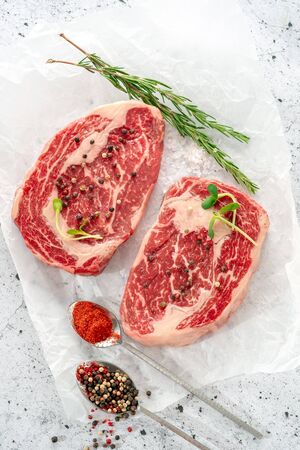 Two raw marbled beef steak ribeye with spices on white Kraft paper. The concept of organic fresh meat, top viewの写真素材