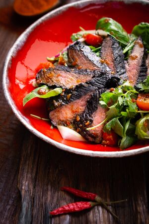 Fillet of beef smoked brisket with green salad on wooden table. Roasted Beef cooking ideaの写真素材