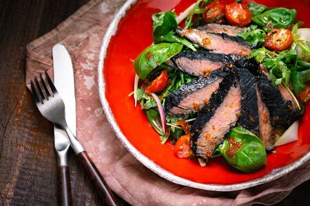 Fillet of beef smoked brisket with green salad on wooden table. Roasted Beef cooking ideaの写真素材