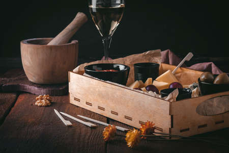 Appetizer for wine. Set of assorted cheeses and snacks on a wooden background in rustic styleの写真素材
