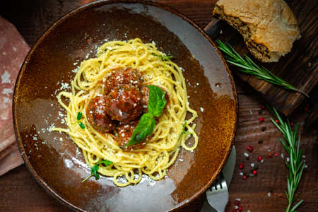 Spaghetti pasta and meat balls in tomato sauce in brown plate with Basil and Parmesan on wooden background. Rustic styleの写真素材