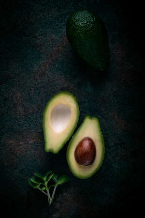 Ripe avocado cut in two on a dark stone background, top view, copy spaceの写真素材
