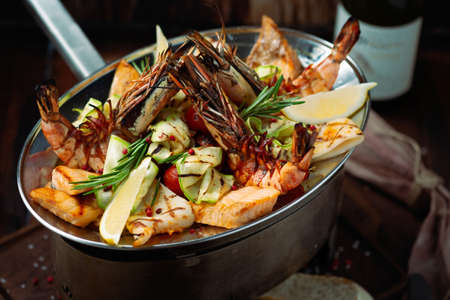 Grilled Mixed Seafoods set in metal plate with shrimp, salmon, squid and perch.