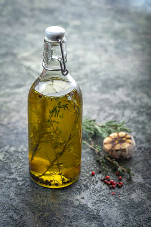 Olive oil in a bottle with rosemary and thyme inside, spicy aromatic cooking oilの写真素材