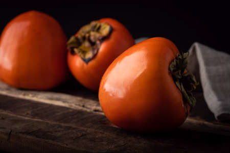 Ripe Persimmon fruit on old wooden table, close-upの写真素材