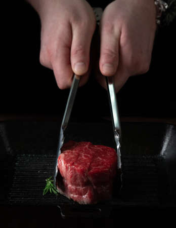 Chef roasts filet Mignon beef steak in a pan with tongsの写真素材