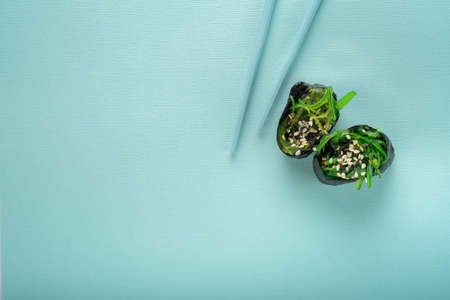 Two Chuka seaweed Sushi with chopsticks on a blue background, top viewの写真素材