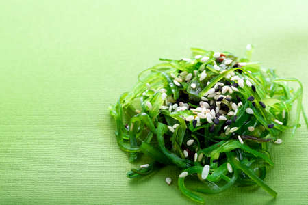 Seaweed salad with sesame seeds on top on a green backgroundの写真素材