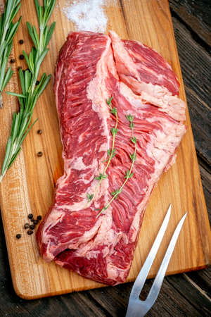 Raw hanging tender or onglet steak of beef on wooden Board with rosemary and thyme on wooden backgroundの写真素材
