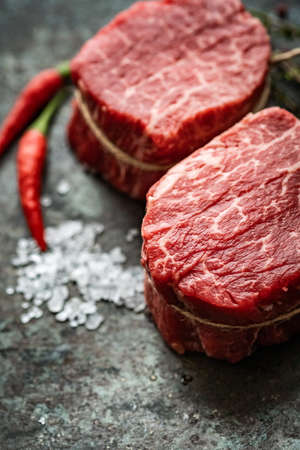 Two juicy filet Mignon beef steaks prepared for grilling with spices and herbs, close upの写真素材