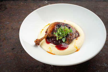 Cooked Duck legs with mashed potatoes with lingonberry sauce and herbsの写真素材