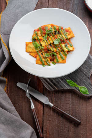 Classic ravioli with tomato sauce and Basil leaves on a white plate, rustic styleの写真素材