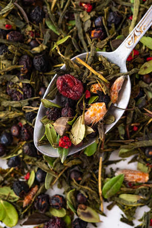 Dried organic green tea with berries and forest herbs on a teaspoon, top viewの写真素材