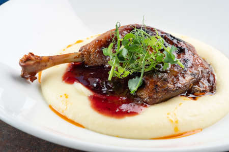 Cooked Duck legs with mashed potatoes with lingonberry sauce and herbs, close upの写真素材